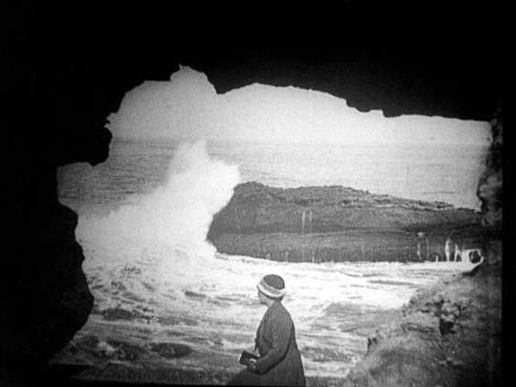     Wellen schlagen gegen die Küste, beobachtet von einer Frau (1914-18)