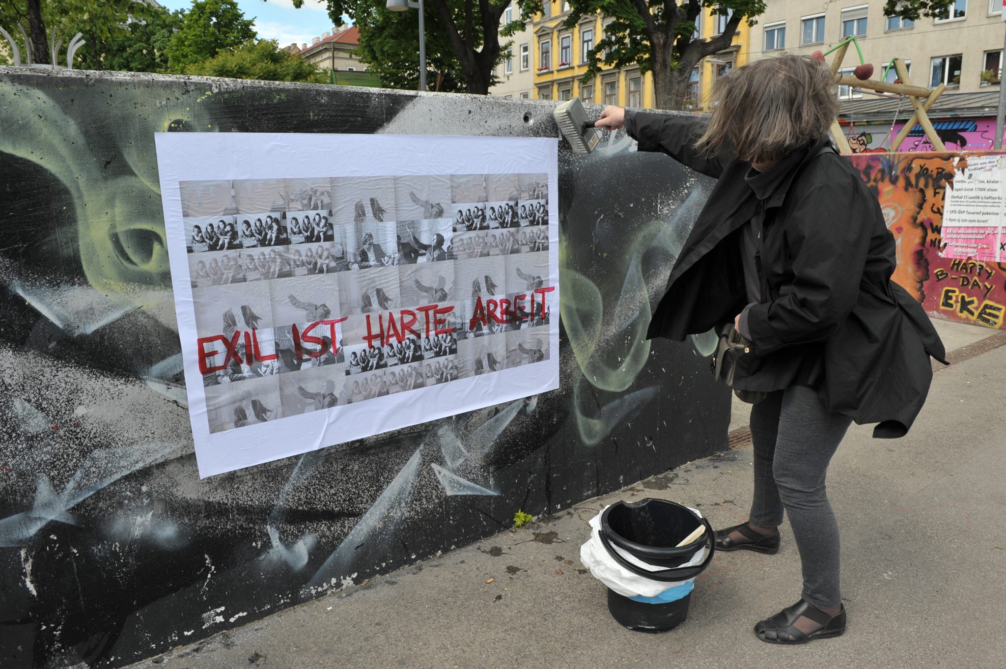Nil Yalter beim Plakatieren im öffentlichen Raum EXIL IST HARTE ARBEIT 2014 Plakataktion in Wien